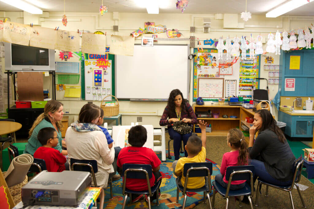 In a school classroom, a presenter is explaining something to the students